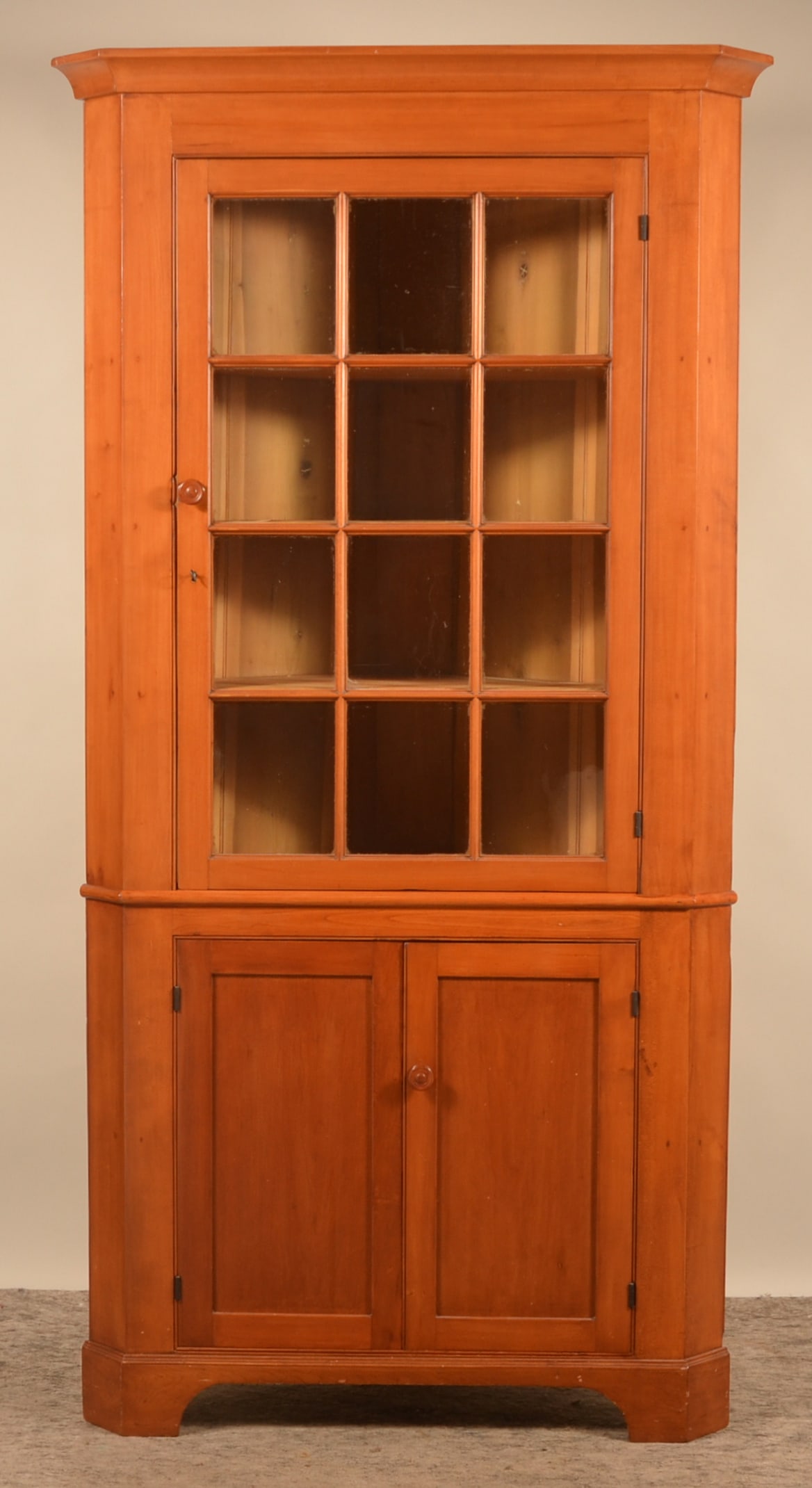 12-Pane Cherry Pennsylvania Corner Cupboard: 2-piece Pennsylvania cupboard. Mortised and pegged, recessed panel doors. 87 1/2"H x 43"W x 20 1/2"D