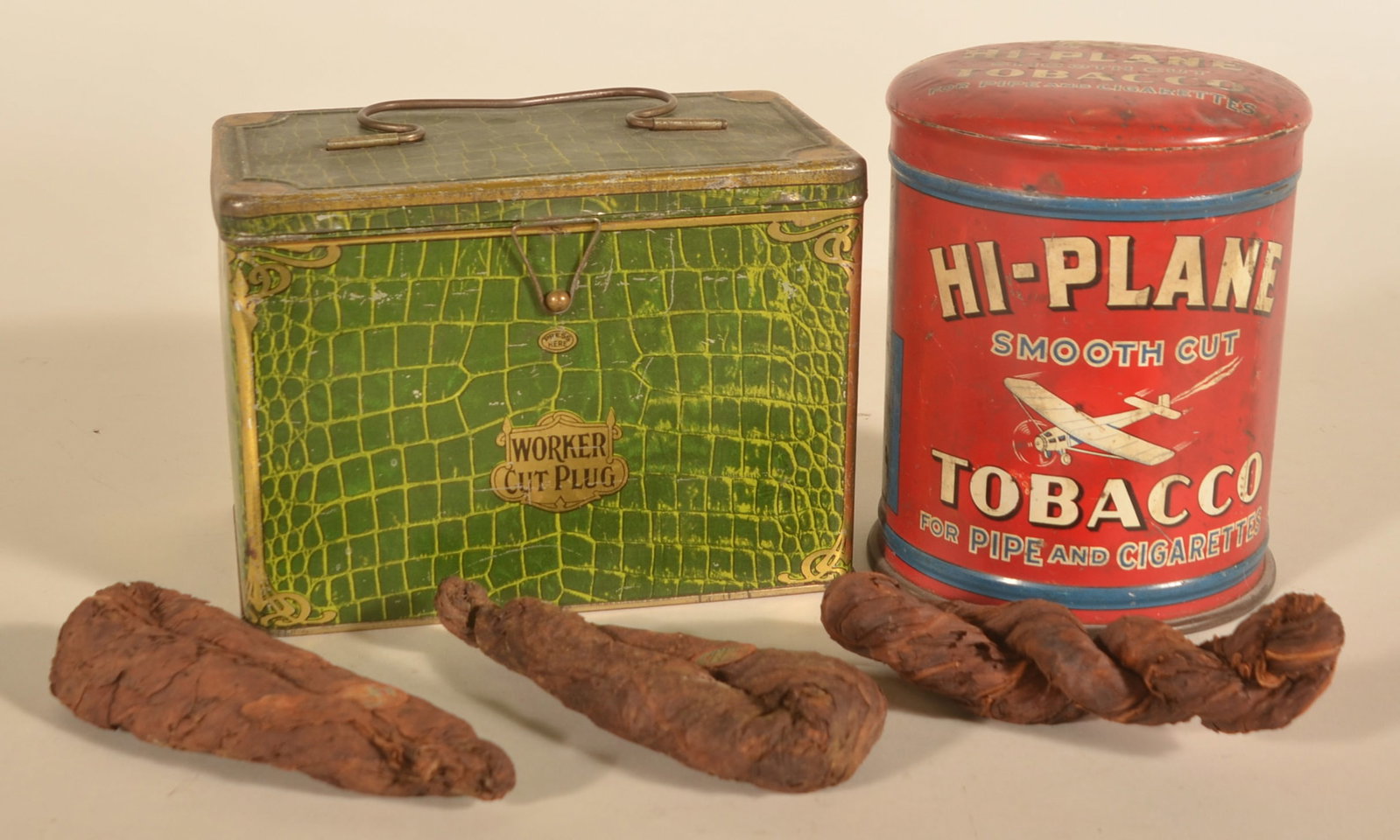 Hi-Plane, Worker & Picnic Twist Tobacco Tins: Nice 1-pound Hi-Plane canister tobacco tin. Worked Cut Plug lunchbox tobacco tin with faux alligatored green leather litho and original keeper. Three original twist plugs of tobacco, two still have th