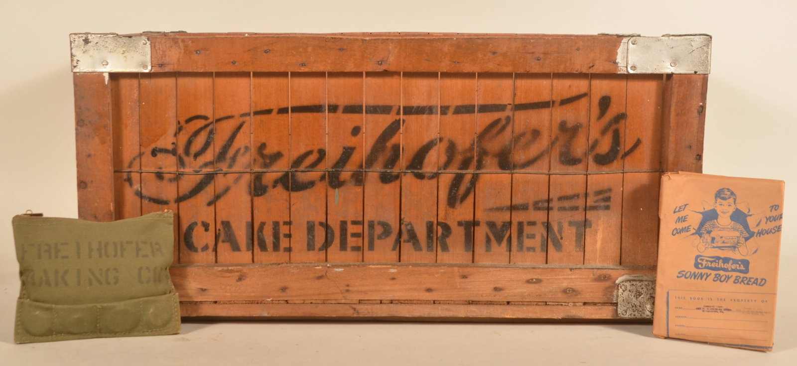 Wood Freihofer's Cake Department Stenciled Crate: Seldom seen wood shipping crate with metal reinforced corners. Stenciled on both long sides with shaped handles at either end. Together with a stenciled camo-color bag with zipper and a grade-school