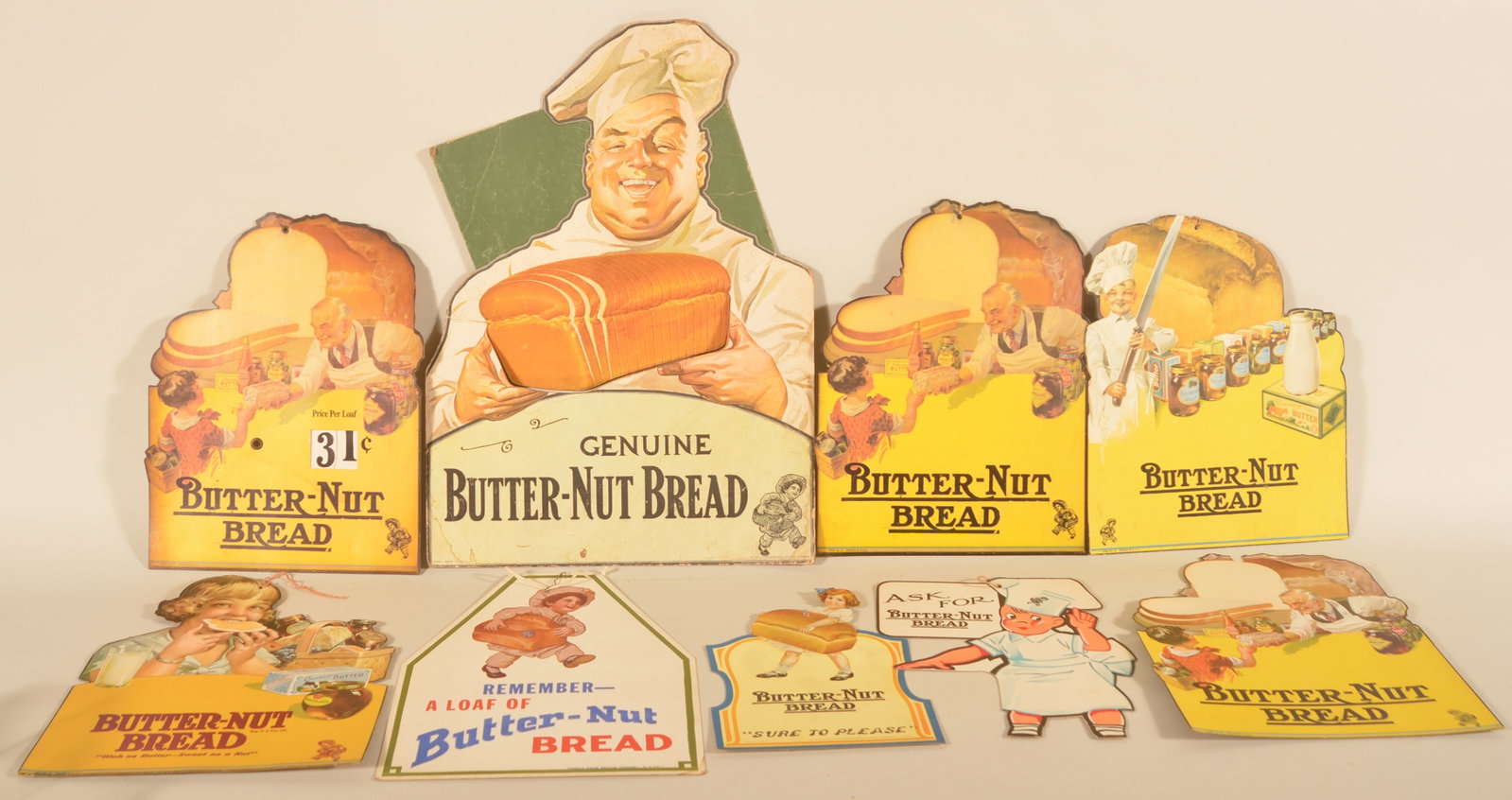 Collection Butter Nut Die-Cut Cardboard Signs: Eight different cardboard counter and hanging signs for Butter Nut Bread. Largest counter display dated 1935. Provenance: The collection of Linda and the late Ed Althouse. Largest, 20 1/4"H x 14 1/2"W