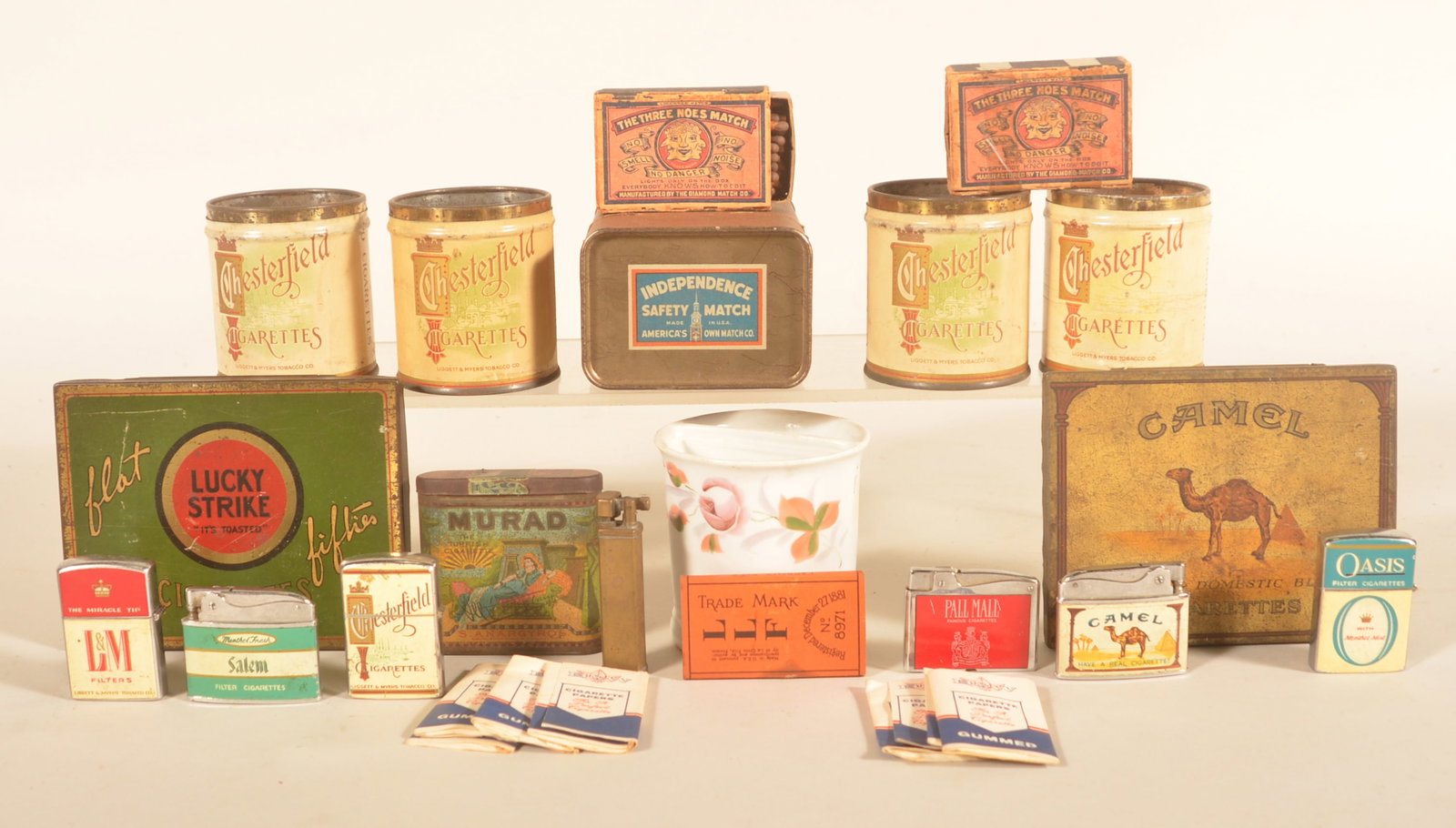 Collection Vintage Cigarette Tins and Ephemera: Nice group of tins including Murad and Chesterfield, cigarette lighters, matches, papers and a shaving mug. Provenance: The collection of Russell and Darlene Snyder. Tallest, 4 7/8"H