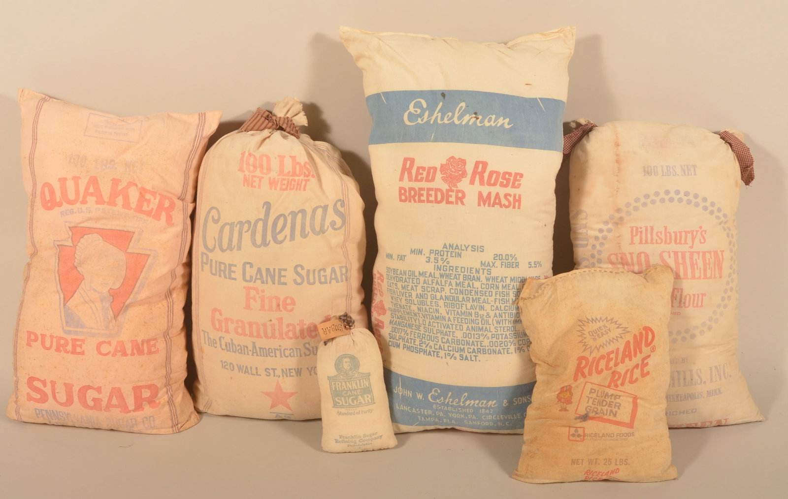 Group of Six Stuffed Advertising Flour Sacks: Advertisements include Riceland Rice, Quaker Sugar, Franklin Sugar, Cardenas Sugar, Pillsbury Flour and Eshelman Breeder Mash. Provenance: The collection of Linda and the late Ed Althouse. Eshelman ba