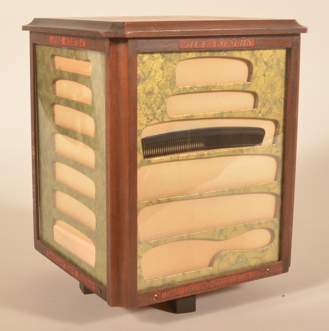 Excellent Ace Combs Revolving 1920s Wood Display: Small countertop revolving wood cabinet with glass displays on three sides and a door with oval mirror on the fourth side. Mahogany case with original labels. Provenance: The collection of Russell