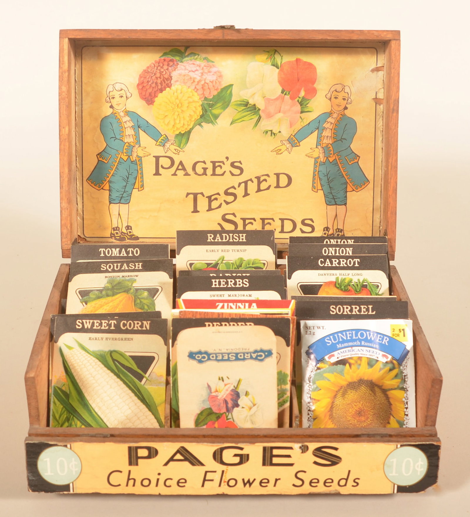 Page's Tested Seeds 10 Cent Counter Display: Oak box with paper labels on inside of lid and on the flip-down front. Complete with a large number of seed packets. Provenance: The collection of Russell and Darlene Snyder. 5 1/4"H x 11"W x 7 3/4"D