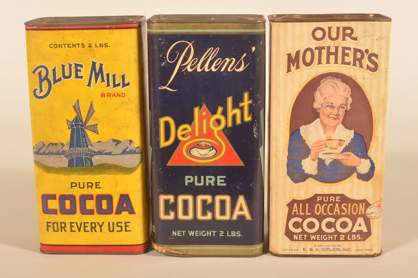 2-Pound Vintage Pure Cocoa Advertising Tins: Cardboard bodies with pry-top, tin lids. Our Mother's, Blue Mill and Pellen's Delight. Provenance: The collection of Russell and Darlene Snyder. 9 3/4"H