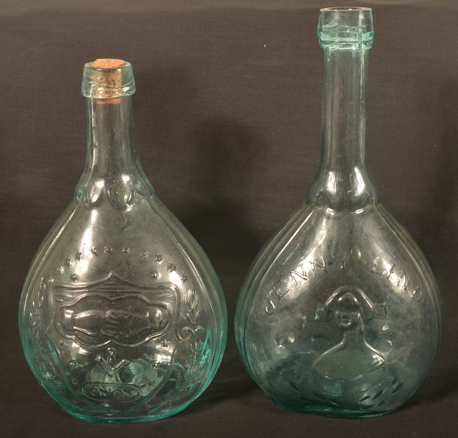 Two Historical 19th C. Glass Flasks: Embossed Jenny Lind with Fislerville Glass Works bottle and a A.R. Samuels (ARS) embossed eagle flask with Masonic logo. Jenny Lind, 10"H