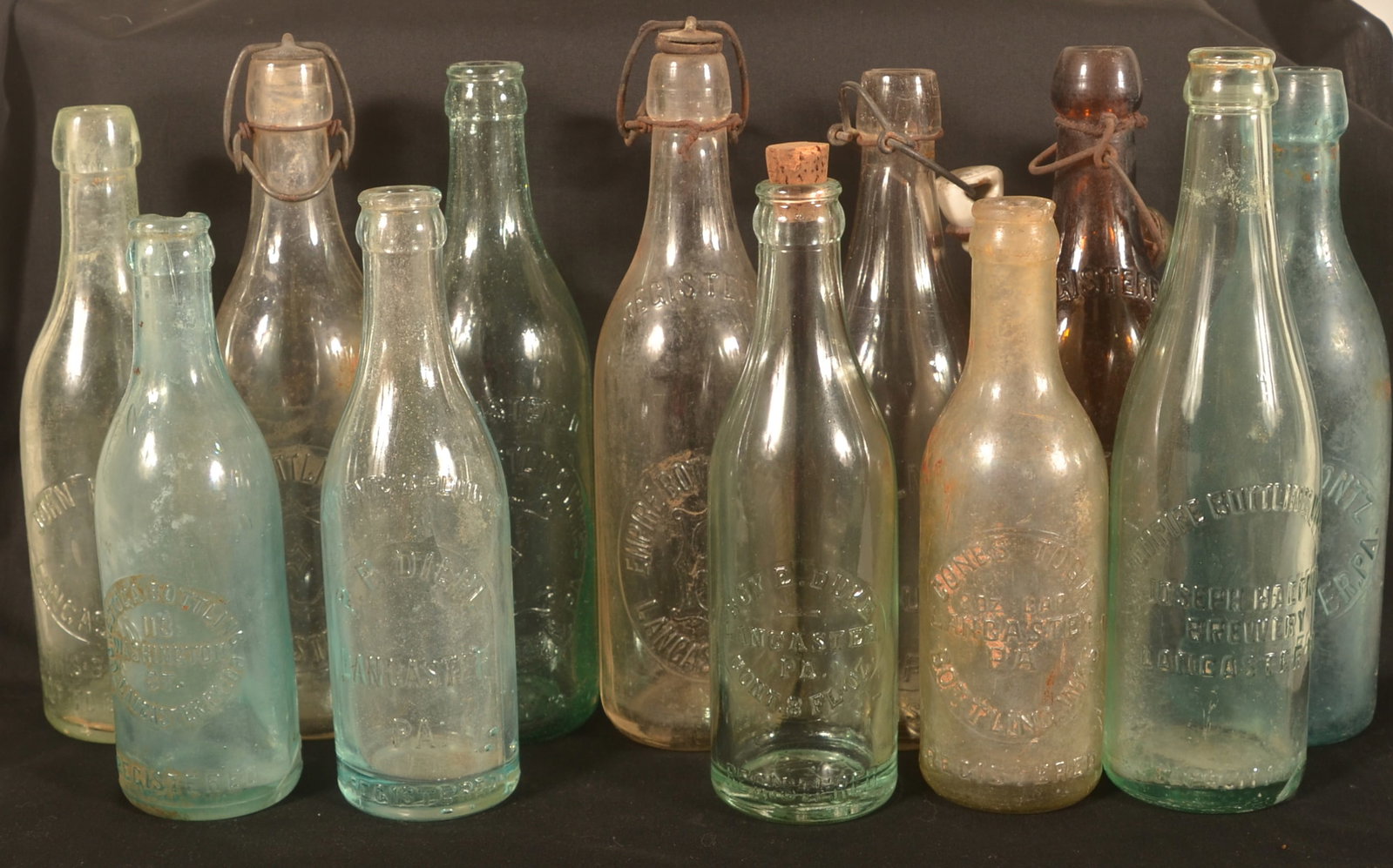 Twelve Antique Lancaster Beer Bottles: Group of bottles from various breweries. Five Empire Bottling Works, two John Pontz (one aqua), Kemmerly (Columbia, Pa), Roy Duke, two Conestoga bottling and one P.P. Diehl. Tallest, 9 1/2"H