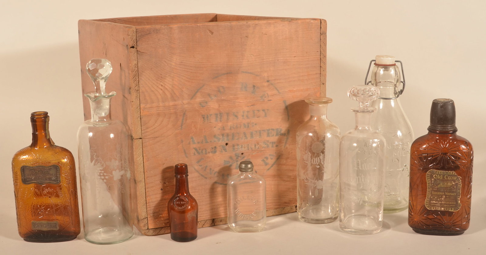 Early Lancaster Shaeffer Whiskey Crate & Bottles: Pine shipping crate with both ends stenciled. Together with an unusual Thatcher's Dairy milk bottle with an embossed farmer milking a cow, small glass Miller whiskey flask, amber "Antique" pure rye