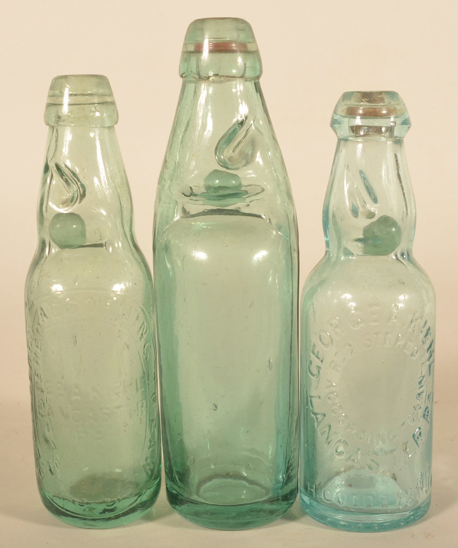 Antique George Kiehl Codd-Neck Soda Bottles: Three bottles total. One unmarked Codd-neck bottle and two embossed George A. Kiehl soda bottles. So named because there is a glass marble in the next that acts as a stopper. Tallest, 9 1/4"H