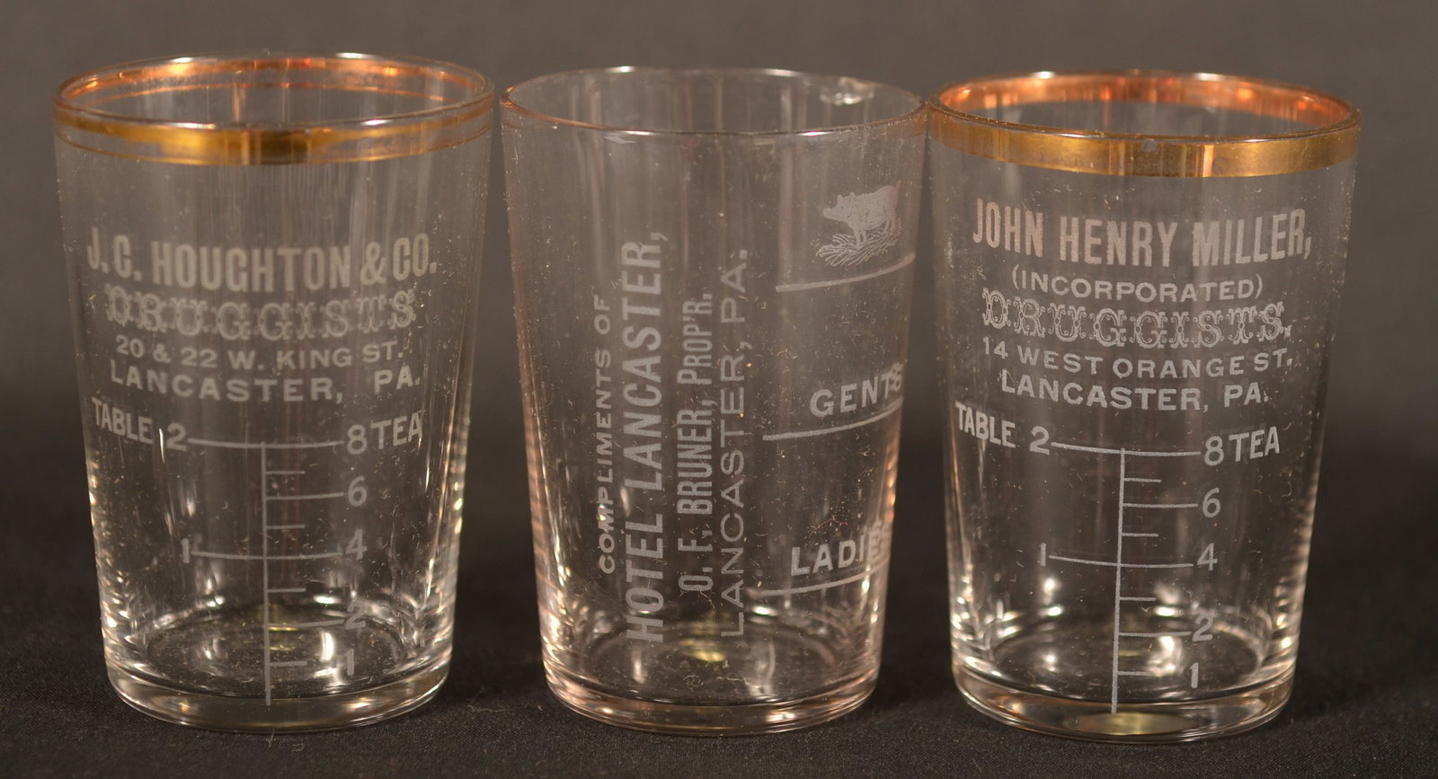 Three Etched Lanc., PA Shot & Measuring Glasses: A great shot glass from the Hotel Lancaster (O.F. Bruner owner) featuring an etched pig and different quantity marks, one for "Gents" and one for "Ladies", a measuring glass with gold gilded rim for