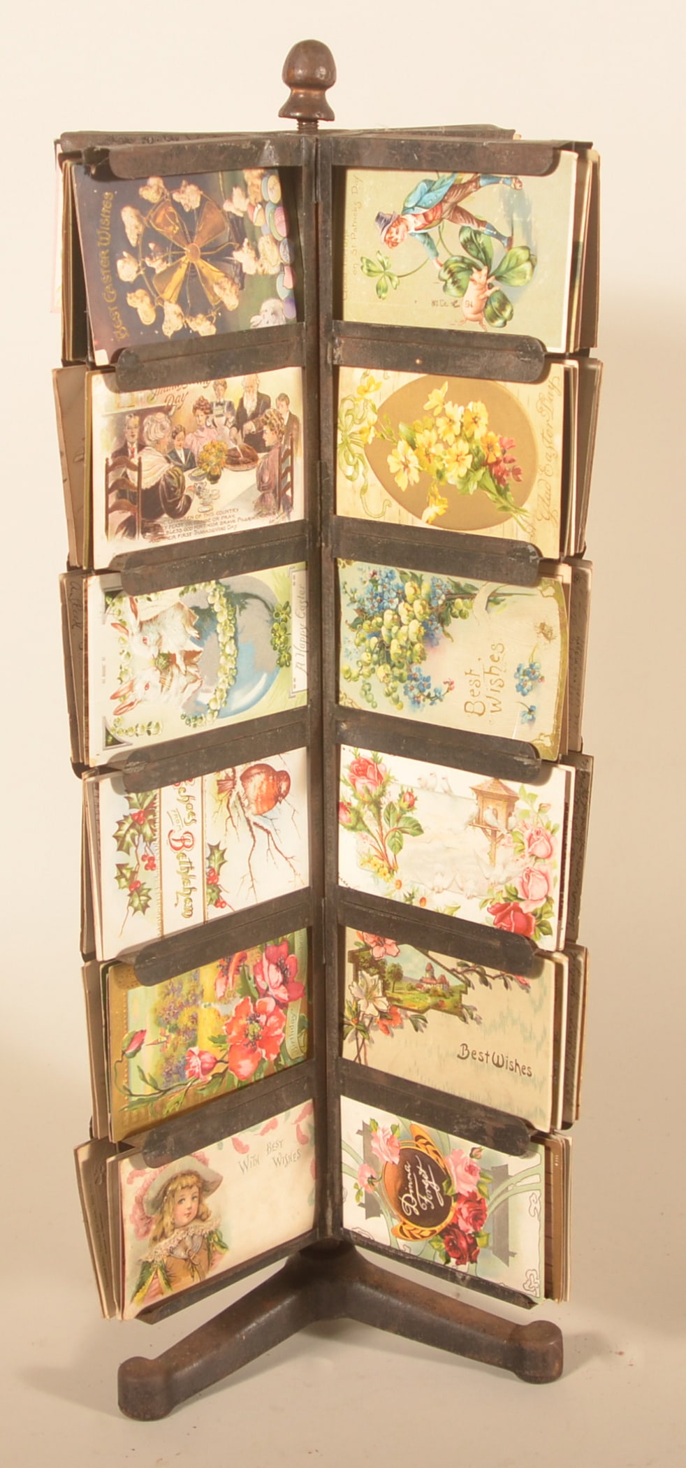 Antique Store Counter Postcard Display: Metal revolving display with a collection of mostly holiday themed postcards. Cast iron base and finial, with original painted surface. Provenance: The collection of Russell and Darlene Snyder. 27"H