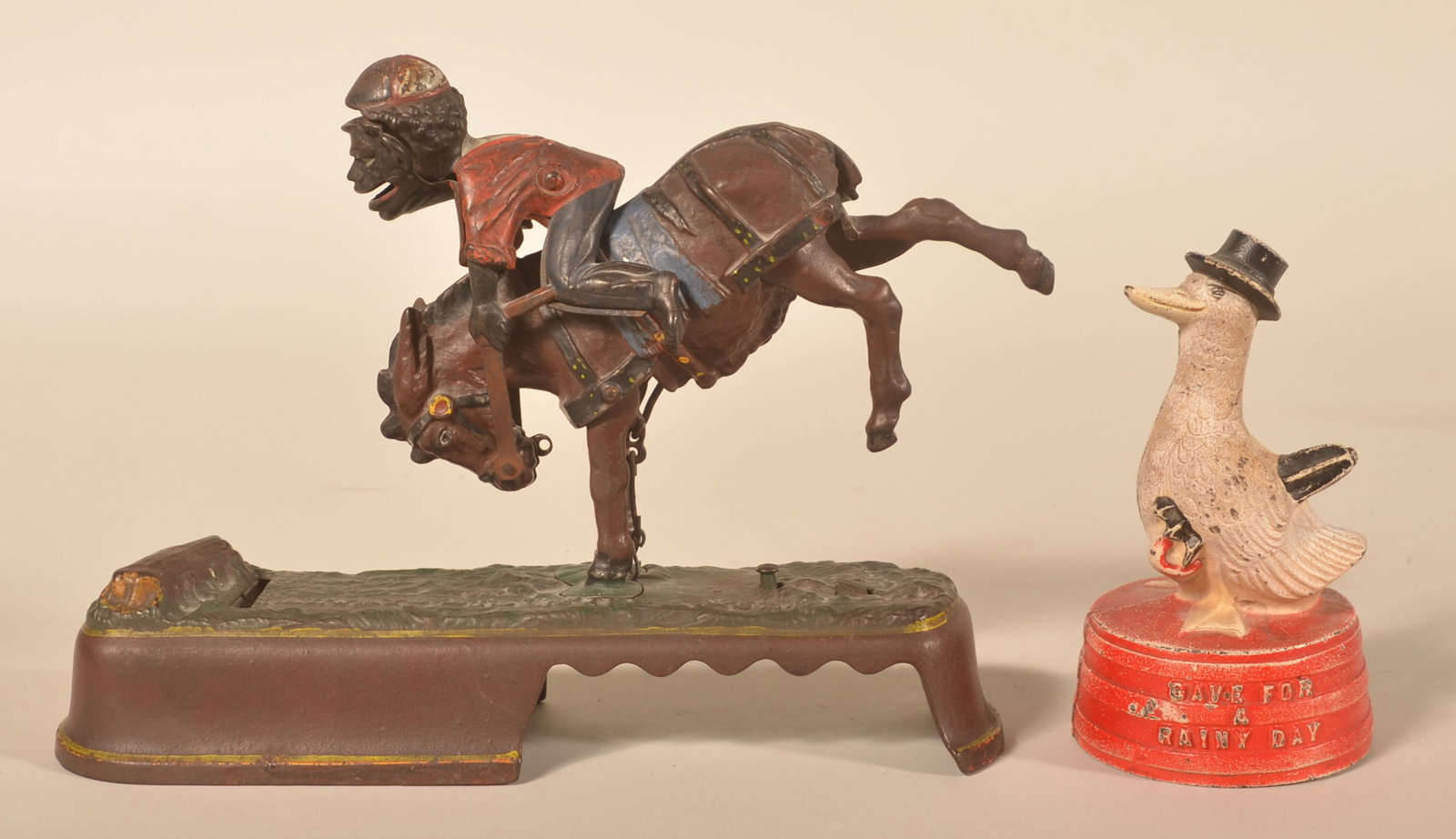"Always Did Spise A Mule" Bank & Duck Still Bank: Mechanical J.E.Stevens bank "Always Did Spise A Mule" with the mule bucking the rider. Together with a still bank featuring a duck holding an umbrella titled "Save For A Rainy Day". Two items. Duck ba