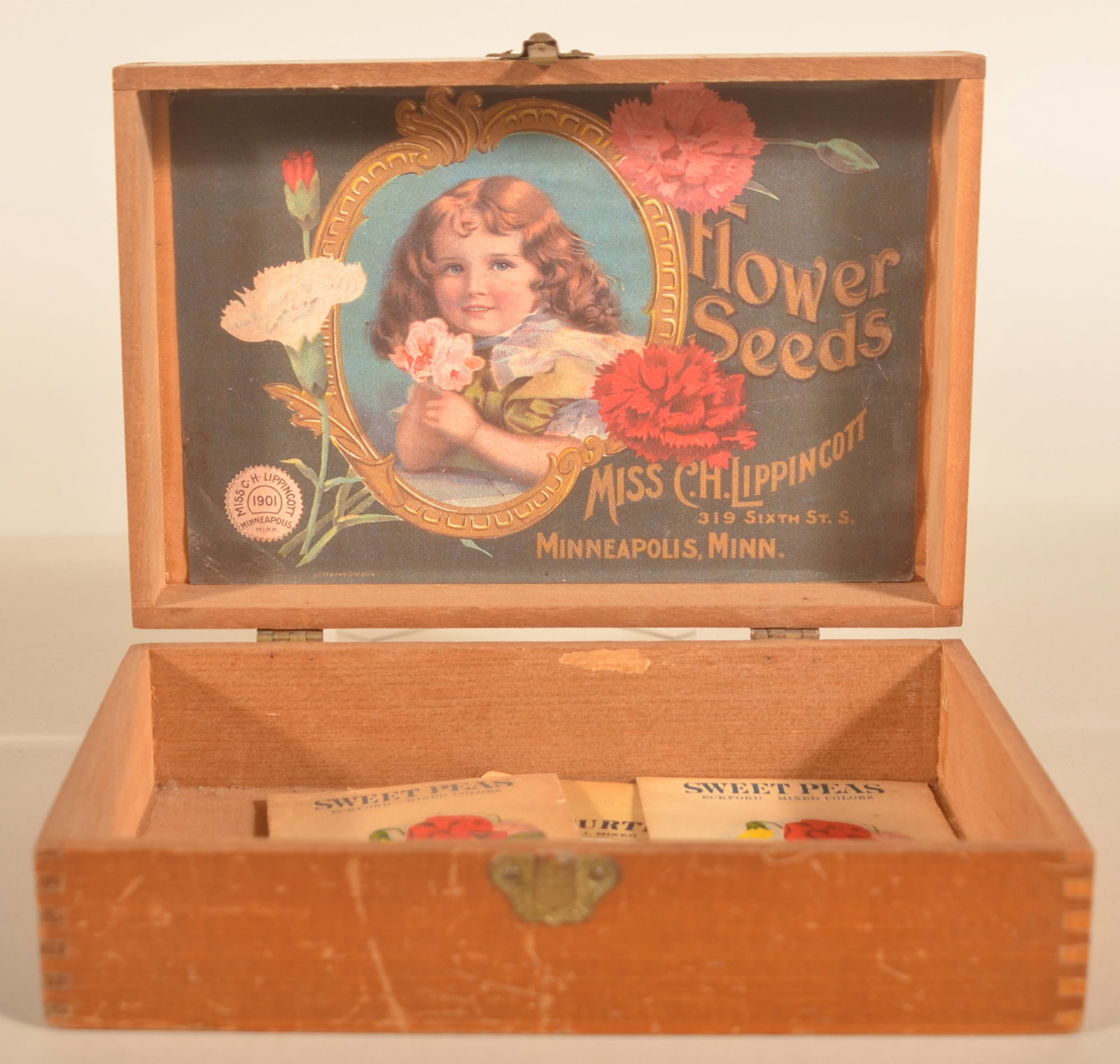 Sweet "Miss C.H.Lippincott" Flower Seeds Box: Small dovetailed display box with interior paper label featuring a smiling girl. Dated 1901. Provenance: The collection of Russell and Darlene Snyder. 2 1/2"H x 7 3/4"W x 5 1/4"D