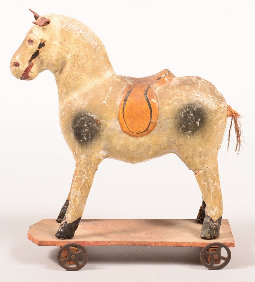 119. Papier Mache Horse Pull Toy on wooden platform: 119. Papier Mache Horse Pull Toy on wooden platform with metal wheels, Unmarked, spotted decorated and yellow saddle, 11-1/2"h.x 9-1/2"l.x 3-1/2"w. Condition: Losses on legs.