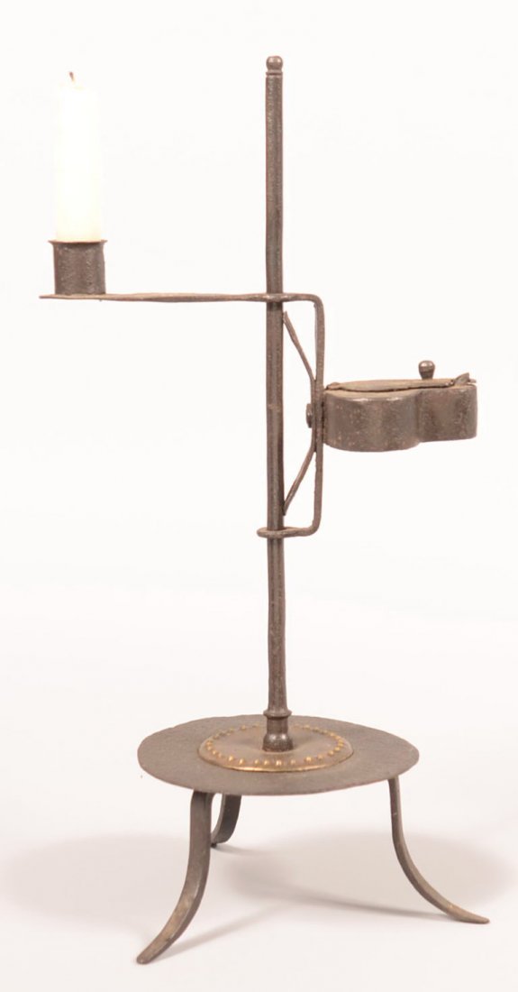 164. Wrought Iron Combination Lamp Stand. Adjustable: 164. Wrought Iron Combination Lamp Stand. Adjustable betty lamp form and candle socket on round shaft, Circular base with brass rosette and three arched legs, 16-1/2"h. Condition: Good.