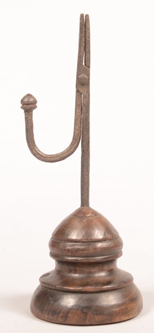184. Wrought Iron Rush Lamp with turned stepped wooden: 184. Wrought Iron Rush Lamp with turned stepped wooden base, scissor type jaws with shaped terminal counter weigh, 9-1/4"h. Condition: Good.