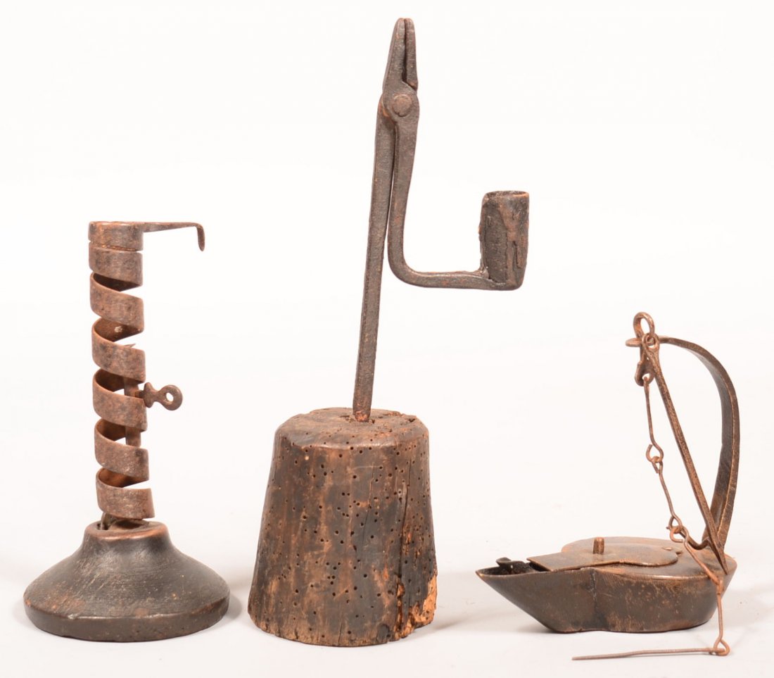 243. Three Pieces of Early Lighting. Wrought Iron Rush: 243. Three Pieces of Early Lighting. Wrought Iron Rush Lamp with Candle Socket counter weight on wooden base, 11"h., Iron Spiraling Candlestick on wooden base, 7-1/4"h. Iron Betty Lamp with arched sup