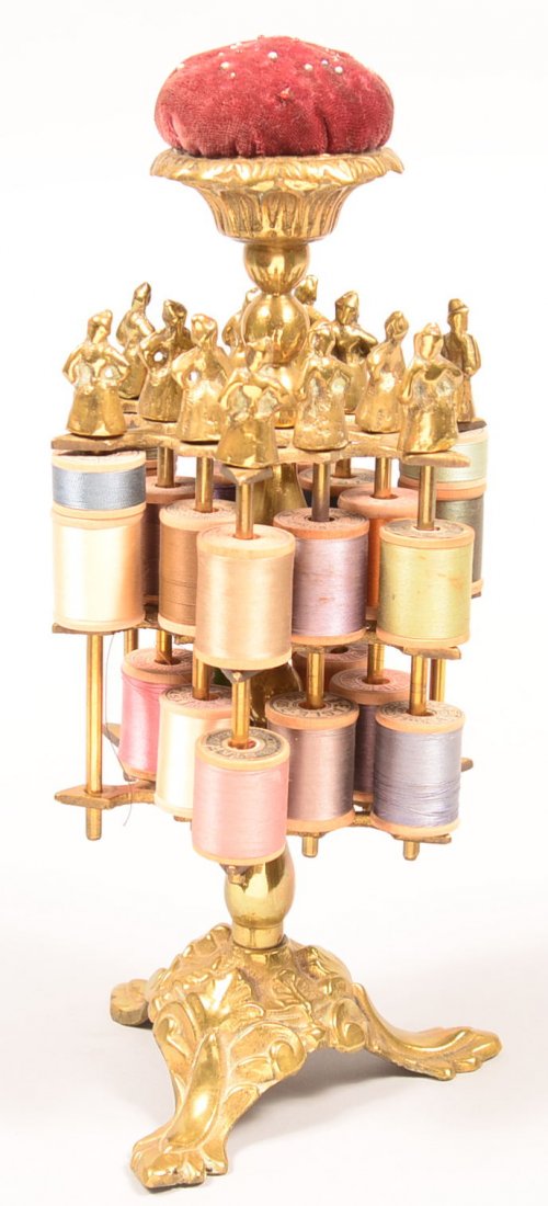 508. Brass Spool Holder with Pin Cushion Top and: 508. Brass Spool Holder with Pin Cushion Top and figural peg finials. Pedestal base with foliate cast triphid base. 12" high. Condition: Good.