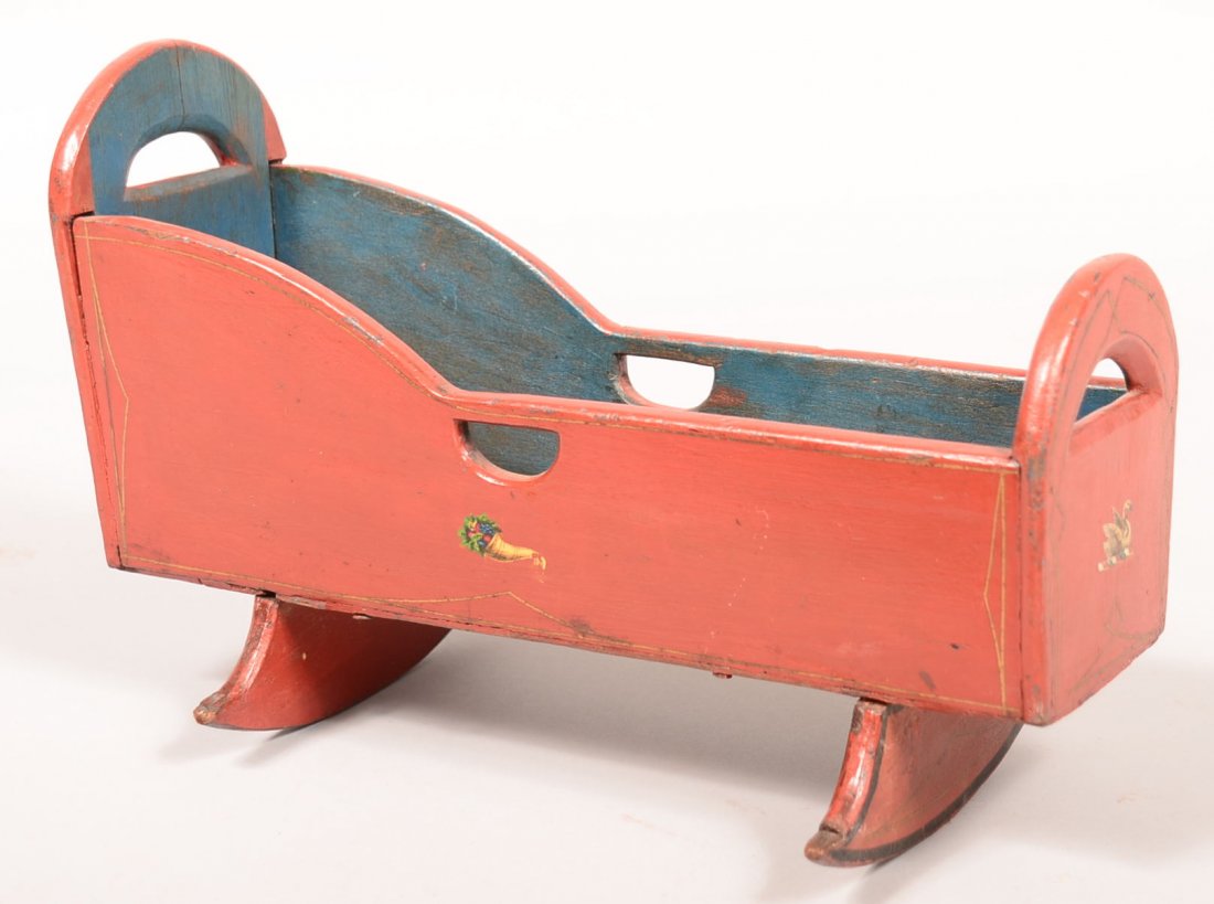 560. Pennsylvania Late 19th Century Painted Wood Doll: 560. Pennsylvania Late 19th Century Painted Wood Doll Cradle. Original red ground with gold and black highlights and decal decorations. Half circular cut-outs with cheese cutter rockers. 8-3/4"h x 13-
