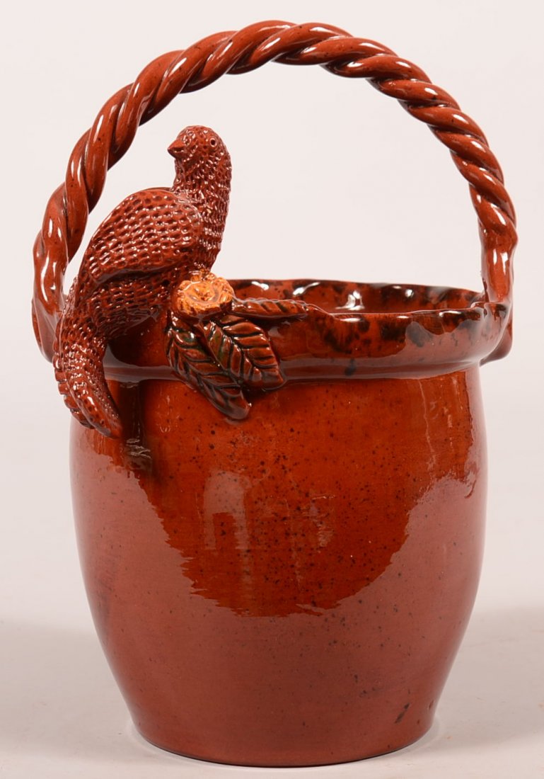 C. N. Foltz Redware Pottery Basket having applied: C. N. Foltz Redware Pottery Basket having applied perched bird and foliage on rim, twisted rope style handle, signed C. N. Foltz 1992, 11"h. Condition: Very good.