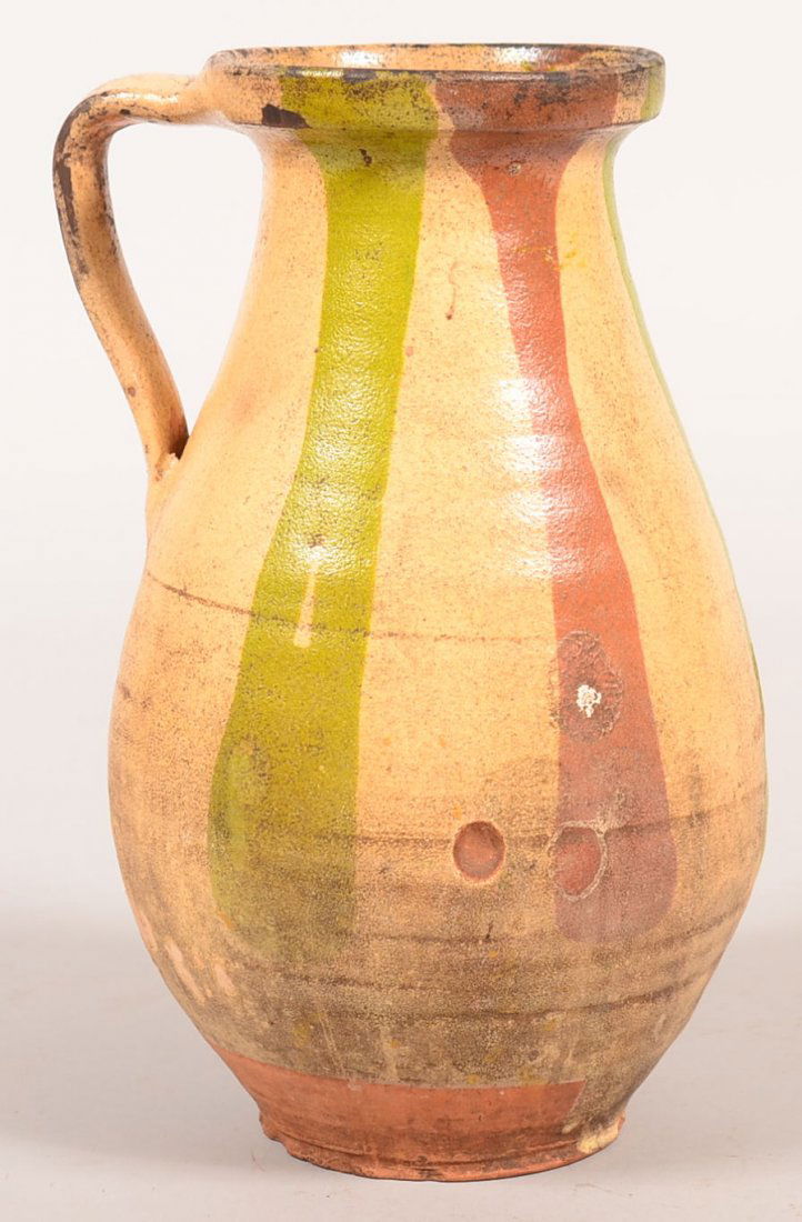 French Redware Milk Jug. Green, yellow rust slip on: French Redware Milk Jug. Green, yellow rust slip on Redware, circa. 1900, 11-1/4"h. Condition: Good with base chips.