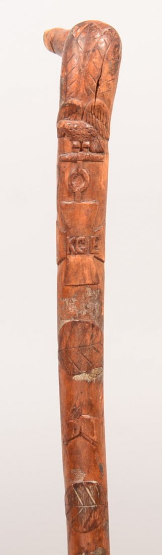 Hand Carved Walking Cane. Having spread wing eagle: Hand Carved Walking Cane. Having spread wing eagle above Maltese cross medal with initials KGE, the top tip shape of dog's head, 36"h. Condition: Good.