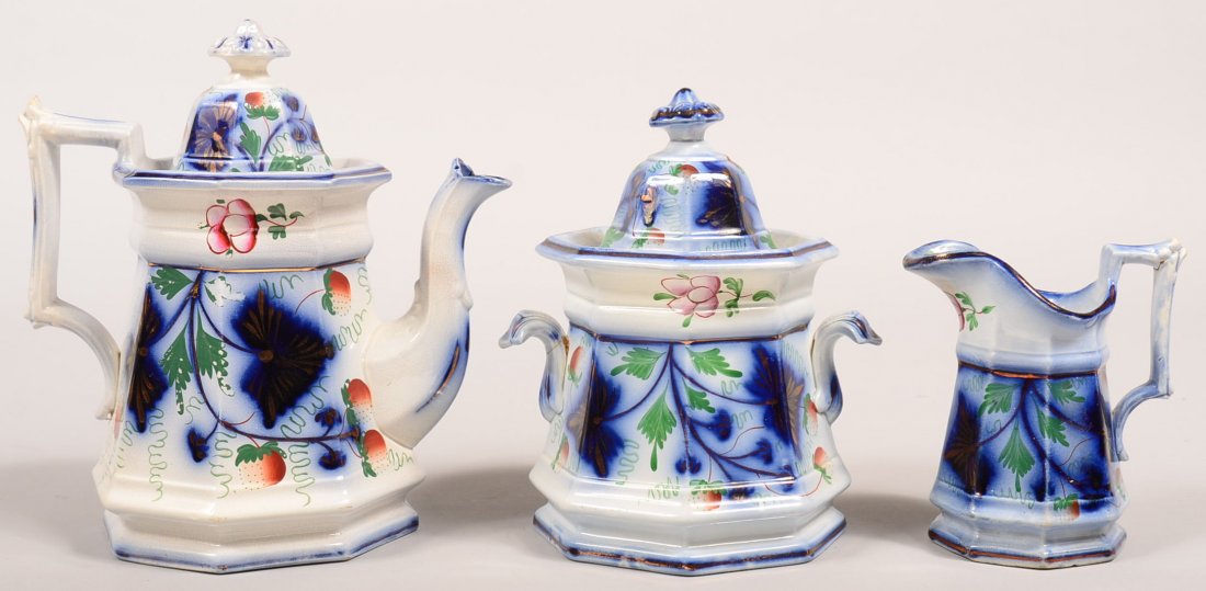Three Pieces of Gaudy Ironstone Flow Blue "Strawberry": Three Pieces of Gaudy Ironstone Flow Blue "Strawberry" Pattern China. Teapot, 9-1/4"h., covered sugar bowl, 8"h. and cream pitcher, 5-1/2"h. Condition: Teapot has a repaired finial on lid, interior ri
