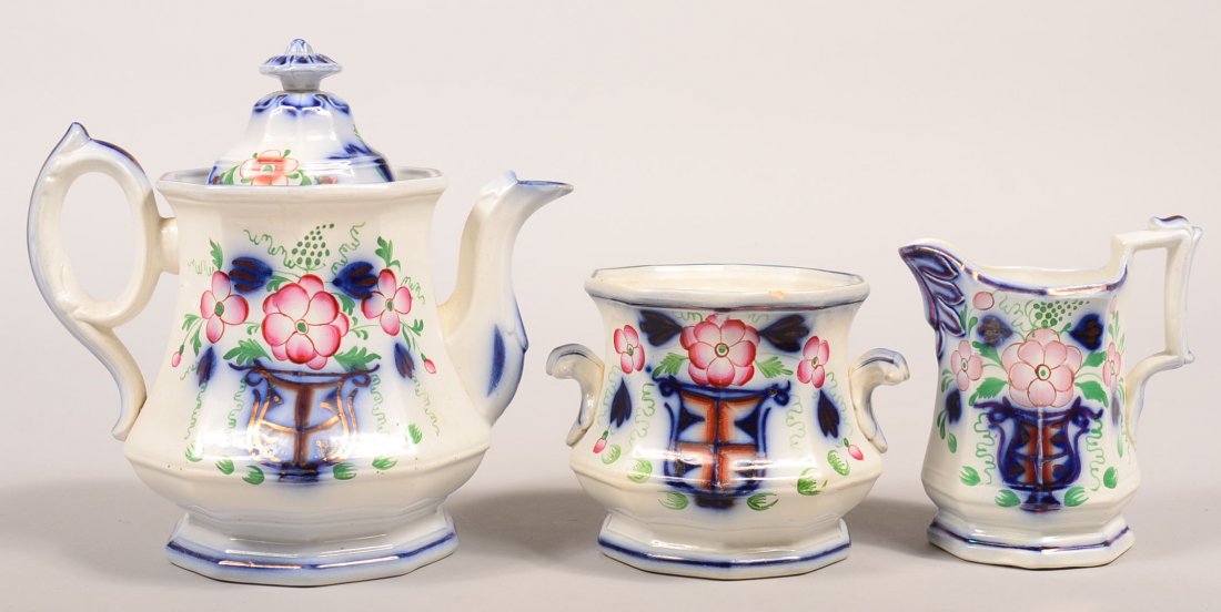 Three Pieces of Gaudy Ironstone Flow Blue "Urn" Pattern: Three Pieces of Gaudy Ironstone Flow Blue "Urn" Pattern China. Teapot, 9-1/4"h., sugar bowl (missing the lid) , 4-7/8"h. and cream pitcher, 6"h. Condition: Teapot has minor glaze wear on edges, sugar