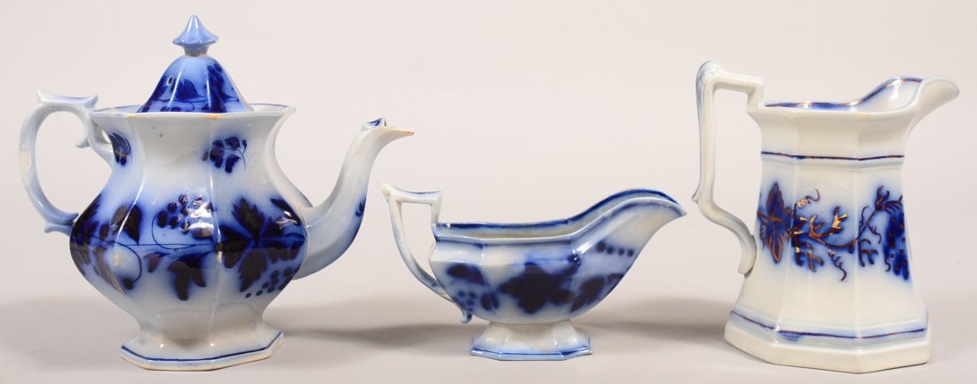 Three Pieces of Flow Blue Brush Stroke Ironstone China.: Three Pieces of Flow Blue Brush Stroke Ironstone China. All variations of grape pattern. Teapot, 9-1/4"h., milk pitcher, 8"h. and sauce boat, 4-1/2"h. Condition: Teapot has a repaired finial on lid an