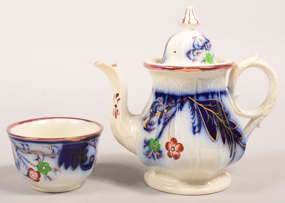 Two Pieces of Gaudy Ironstone Flow Blue "Fern and: Two Pieces of Gaudy Ironstone Flow Blue "Fern and Flower" Pattern China. Teapot, 10-1/2"h. and 3-1/2" waste bowl. Condition: Teapot has repaired finial on lid and hairline on base, waste bowl is good.