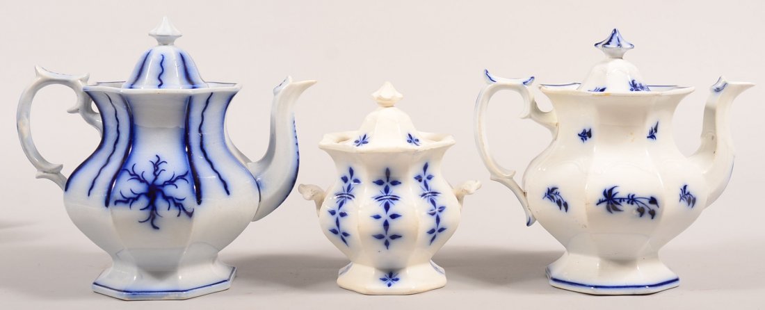 Three Pieces of Flow Blue Brush Stroke Ironstone China.: Three Pieces of Flow Blue Brush Stroke Ironstone China. "Seaweed" pattern 10" teapot, "Sprig" pattern 9-1/2" teapot and "Diamond Leaf Cross" covered sugar bowl, 7-5/8"h. Condition: Seaweed teapot has