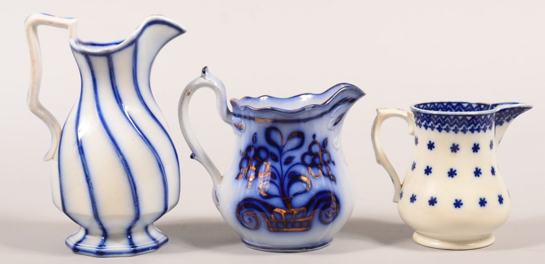 Three Flow Blue China Pitchers. "Snowflake" stick: Three Flow Blue China Pitchers. "Snowflake" stick spatter, 4-3/4"h., Brush stroke "Urn", 6-1/4"h. and "Swirl", 8"h. Condition: Snowflake is good, Urn has glaze loss on handle and swirl has a repaired