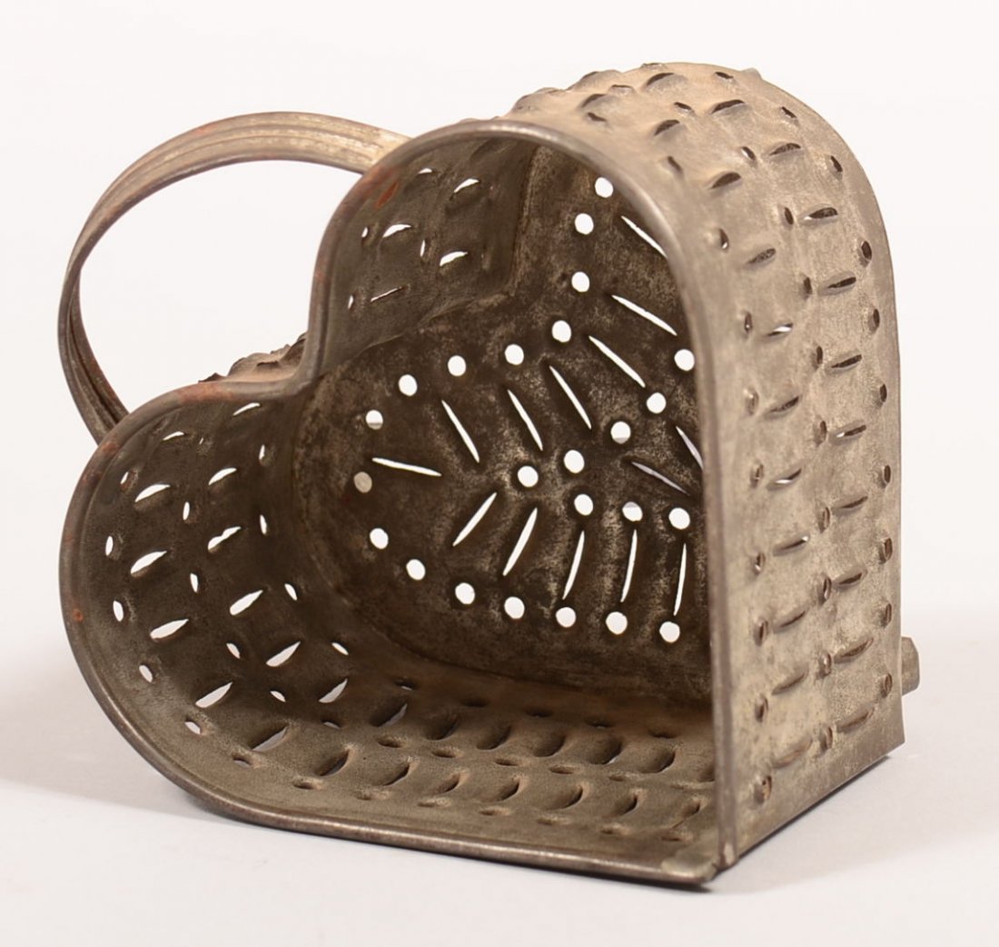 Punch Tin Cheese Heart Shape Mold. Folded and soldered: Punch Tin Cheese Heart Shape Mold. Folded and soldered construction, applied handle and angled feet, 4"h. Condition: Very good.