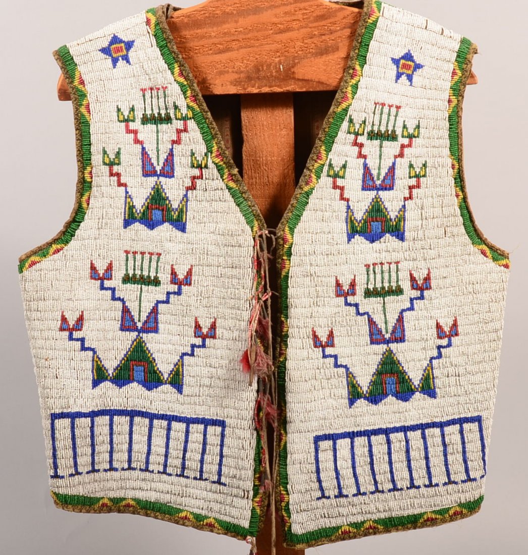 A very good antique Sioux Indian man's vest - fully: A very good antique Sioux Indian man's vest - fully beaded with typical 1880's geometric motifs lined with a cotton fabric and having porcupin quill wrapped, buckskin thongs as closesures tin cone and