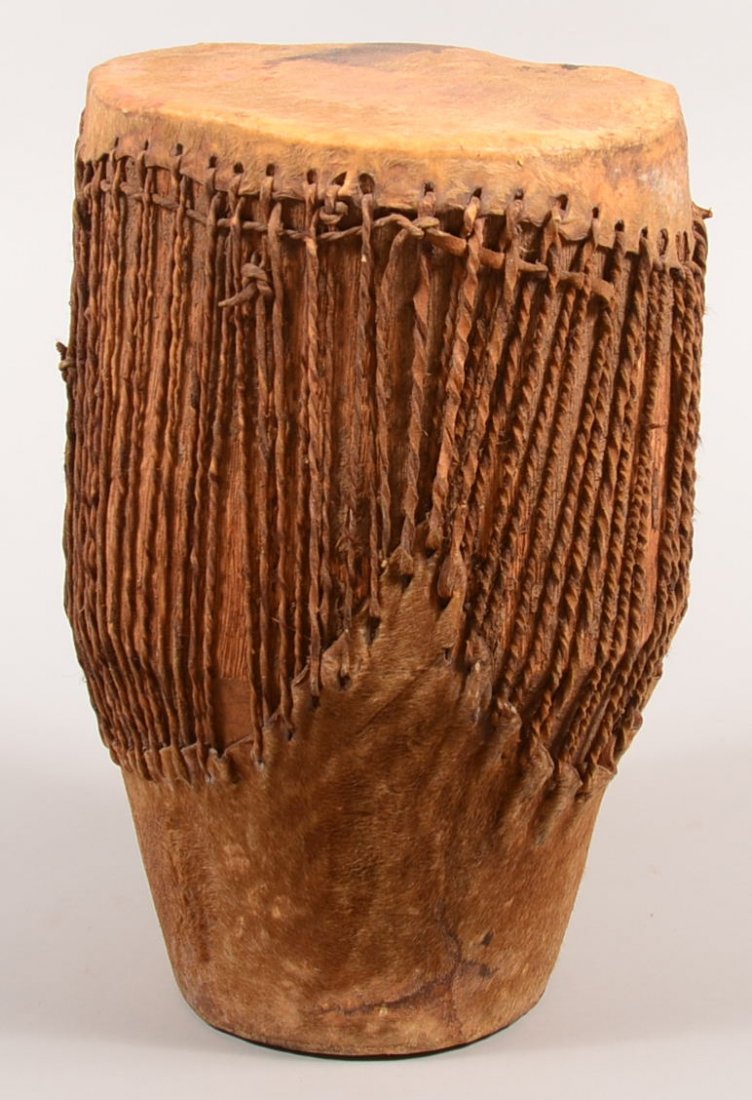 An African tribal drum 16 1/2" tall with hollow wood: An African tribal drum 16 1/2" tall with hollow wood body and antelope skin head and binding thongs