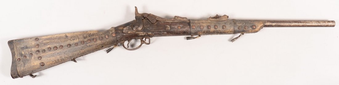 An 1878 model Springfield "trapdoor" carbine - broken: An 1878 model Springfield "trapdoor" carbine - broken stock at the wrist and covered with rawhide at the butt and fore end - "tacked-up" in the style of a Plains Indian warrior's gun