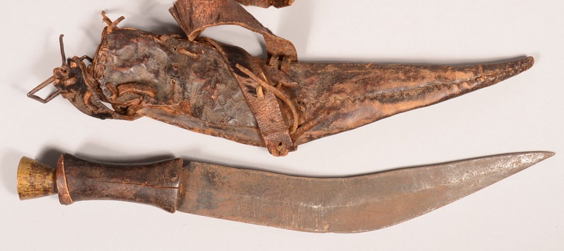 Very old kukri having a 12-3/4" blade, wood grip with: Very old kukri having a 12-3/4" blade, wood grip with flared brass pommel, and a leather sheath with belt. Condition: untouched patina overall showing much wear.
