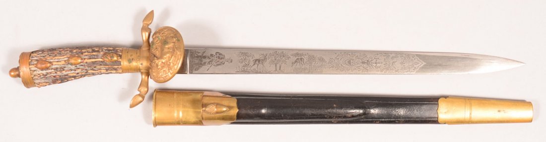 German hunting cutlass by WKC having a 15-1/8" tripple: German hunting cutlass by WKC having a 15-1/8" tripple etched blade detailing hunting scenes. It has a brass mounted leather scabbard, a brass hilt, stag grip, and stag on the guard clamshell. Conditi