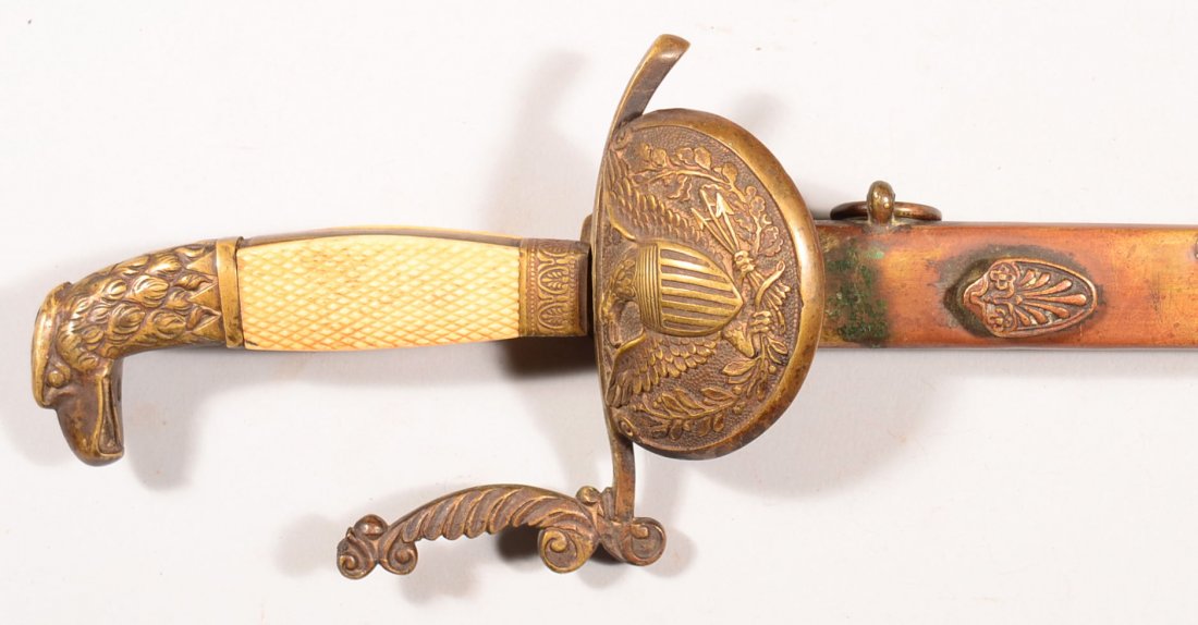 U.S. early 19th century eagle head militia sword having: U.S. early 19th century eagle head militia sword having a 31-3/4" blade with a panoply of arms each side, a brass scabbard, checkered bone grip, brass hilt, and a patriotic eagle on the clamshell. Con