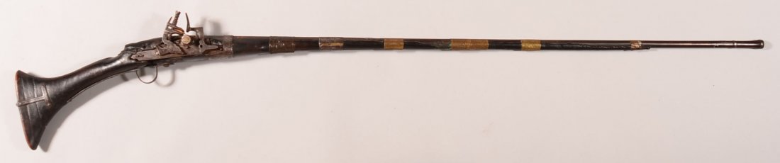 North African snaphaunce musket having a wood butt: North African snaphaunce musket having a wood butt flaring to 7" by 1-1//2". It has a thin octagon to round barrel 50-1/4" long with a bulbous flared muzzle and (6) engraved brass bands and (2) engrav