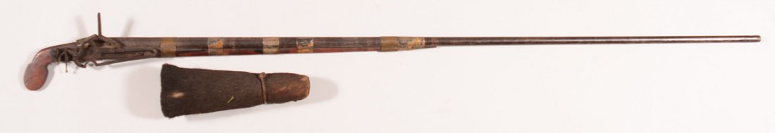 Far Eastern miquelet musket having a 46" round barrel: Far Eastern miquelet musket having a 46" round barrel with (8) silver plated brass barrel bands and includes an animal hide cover to protect the lockworks. 51-1/4" o/a. Condition: good having untouche
