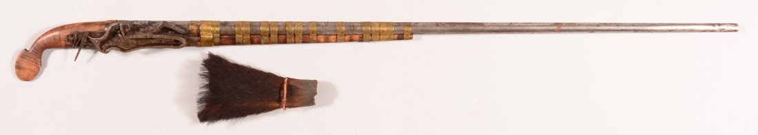 Far Eastern miquelet musket having a 42-3/4" round: Far Eastern miquelet musket having a 42-3/4" round barrel with (16) brass barrel bands and includes an animal hide cover to protect the lockworks. 49-3/4" o/a. Condition: good having been cleaned in t