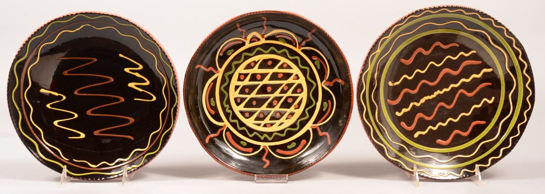 Three Breininger Redware Pottery Manganese ground: Three Breininger Redware Pottery Manganese ground Plates with various slip decoration. Two dated 1990, one dated 1981. 10-1/4" to 10-1/2" diam. Condition: Very good.