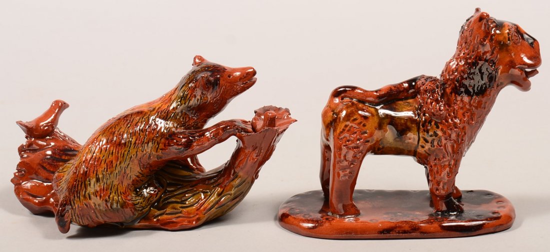 Two Breininger Hand Molded and Glazed Redware Pottery: Two Breininger Hand Molded and Glazed Redware Pottery Animal Figures. Bear standing on a stump raiding a bird nest, dated 1986, 7"l.. and a lion on an oval slab base sticking his tongue out of his mou