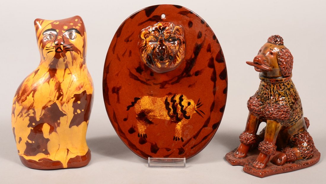 Two Breininger Redware Pottery Figurines and a Wall: Two Breininger Redware Pottery Figurines and a Wall Plaque Hot Plate. 1st: Seated poodle, 7-1/4"h. 2nd: Marbleized glazed seated cat, 8"h. 3rd: Wall plaque with embossed lion head decoration, 8-1/4"h.