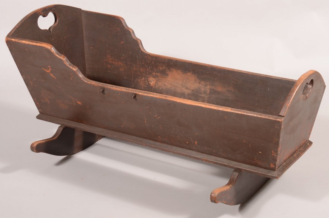 Pennsylvania 19th Century Cherry Cradle with original: Pennsylvania 19th Century Cherry Cradle with original brown paint. Arched headboard and footboard with heart cut-outs, dovetailed case and cheese cutter rockers. 22-1/2"h. x 24"w. x 45-1/2"l. Conditio