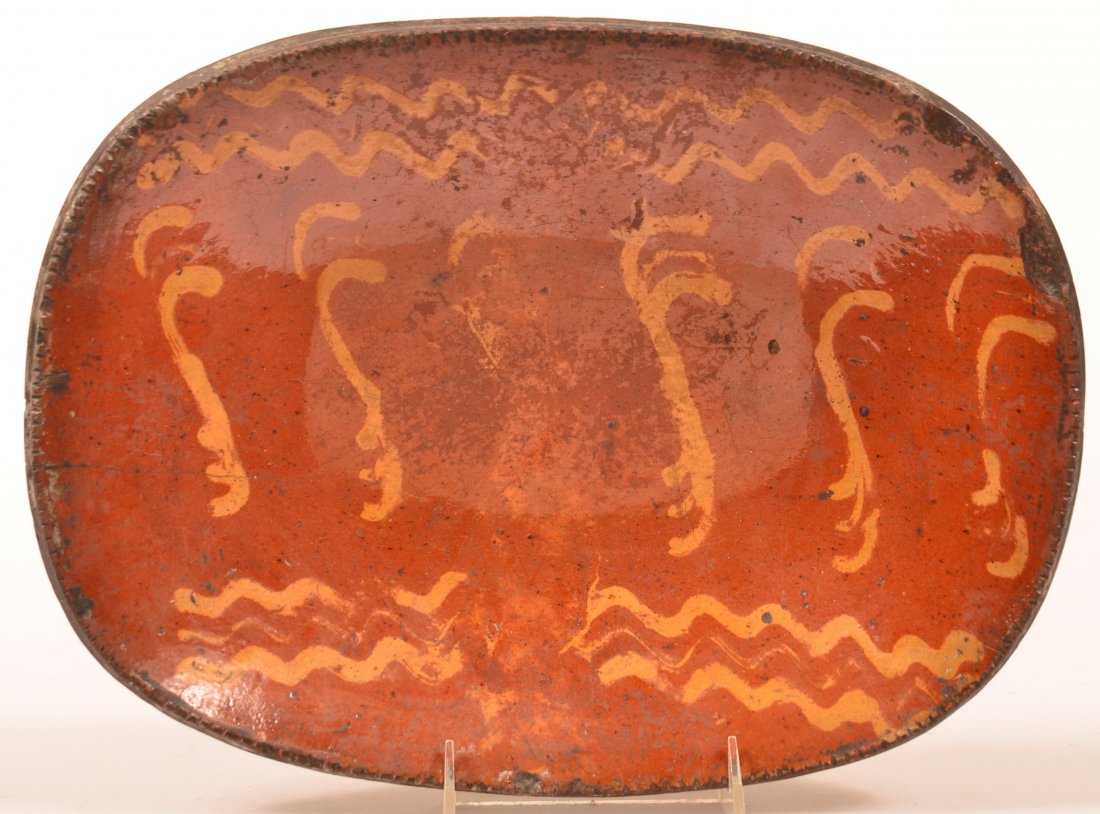 Pennsylvania 19th Century Redware Pottery Slip: Pennsylvania 19th Century Redware Pottery Slip Decorated Platter. Swags and zig-zag lines slip decorations, coggle wheel rim. 10" x 13-1/4". Condition: Good with hairline and edge chips.