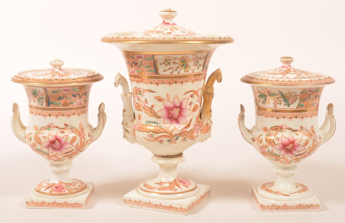 Three Piece Early 19th Century Hard Paste Porcelain: Three Piece Early 19th Century Hard Paste Porcelain Garniture Set. Unmarked, possible Coalport. Three covered urns with floral and foliate polychrome decoration. 8" and 10-1/2" high. Condition: Smalle