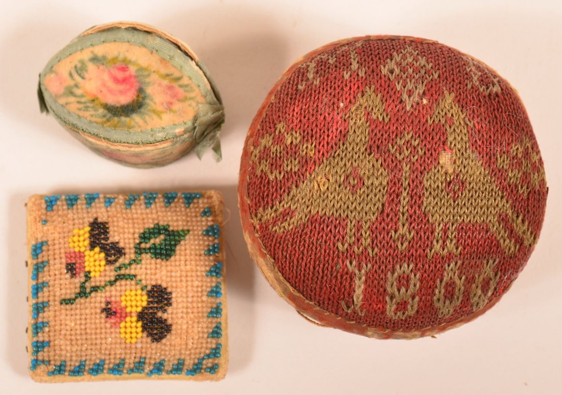 Two Antique Sewing Pin Cushions and a Thimble Case.: Two Antique Sewing Pin Cushions and a Thimble Case. Ball pinn cushion has love bird needlework and is dated 1800, 3" diam. Condition: Good with wear and losses.