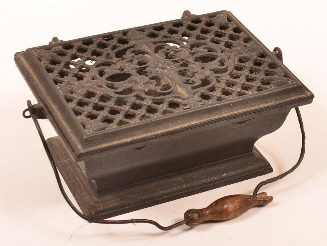 Victorian Cast Iron Foot Warmer with open work hinged: Victorian Cast Iron Foot Warmer with open work hinged lid, Bail handle with wood hand grip, 4-1/2'h. x 11-1/2"w. x 7-1/2"d. Condition: Good with handle grip with loss.